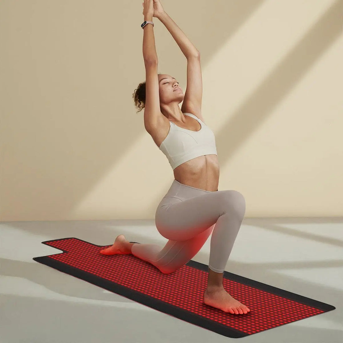 Woman stretching on a red infrared light therapy mat glowing red beneath her