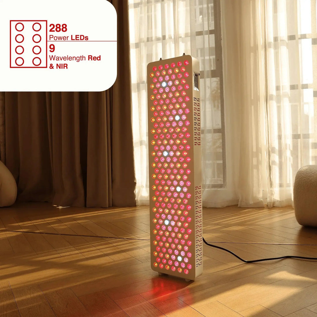 Red light therapy panel standing on a wood floor by a sunlit window, glowing red