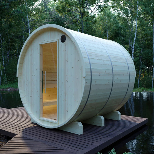 Finnish barrel sauna on a deck beside a forest lake at dusk, glass door open to a warmly lit cedar interior
