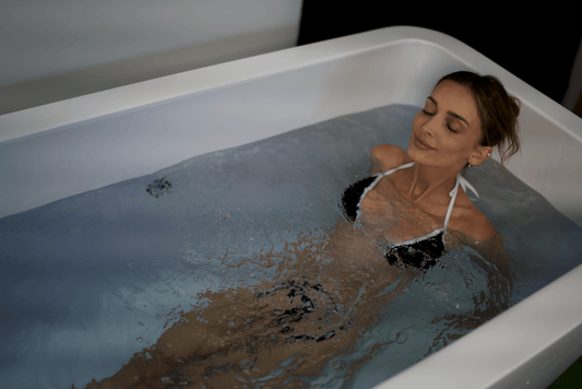 Woman submerged in a white cold plunge tub filled with cold water