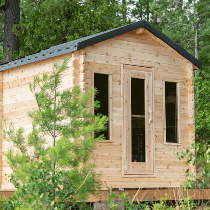 Canadian Timber Georgian 6-person white cedar cabin sauna, set up in a wooded clearing