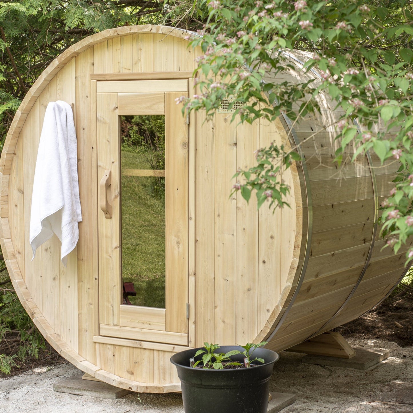 Canadian Timber Harmony 4-person white cedar barrel sauna, installed in a garden setting
