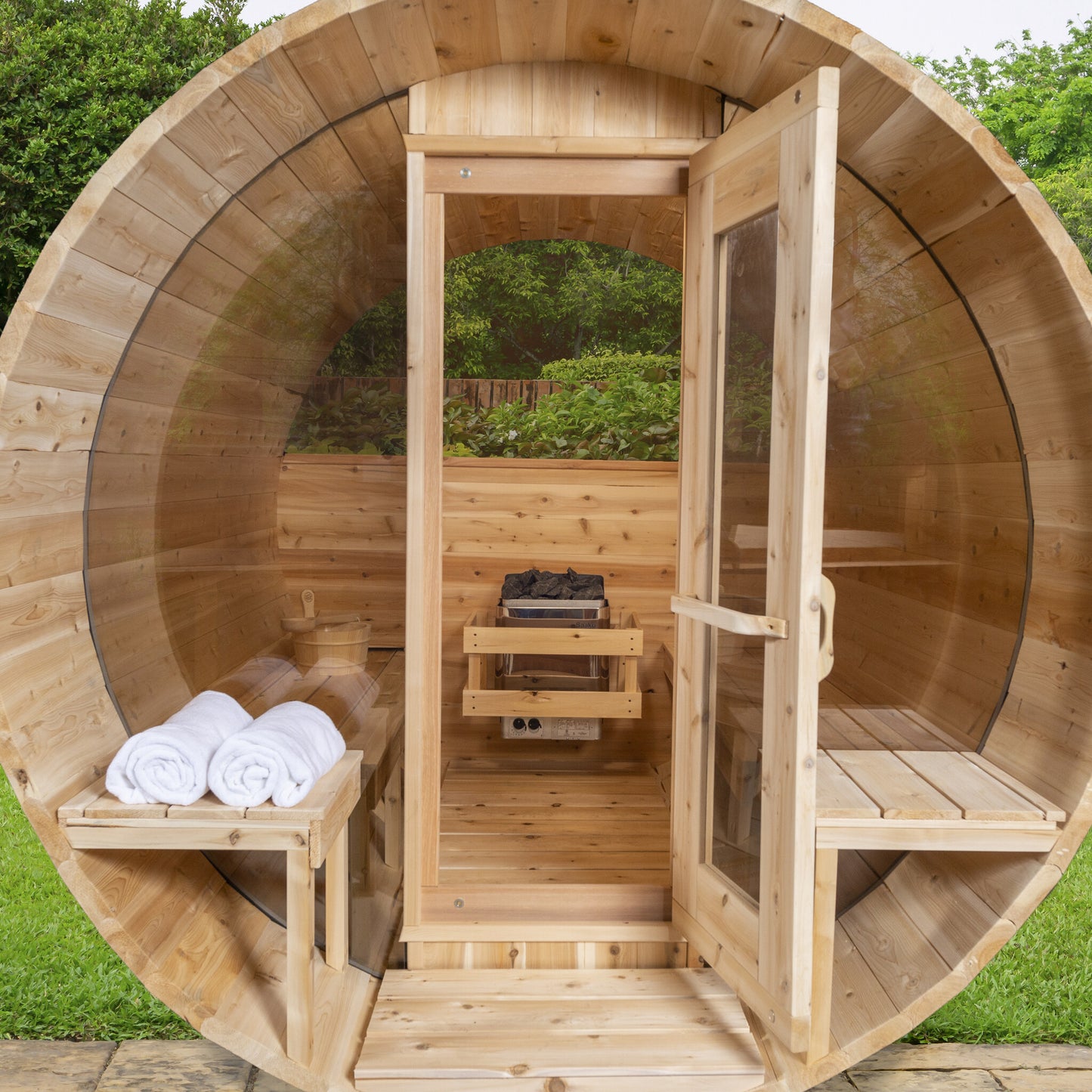 Canadian Timber Serenity with Windows 5-person white cedar barrel sauna, installed in a garden setting
